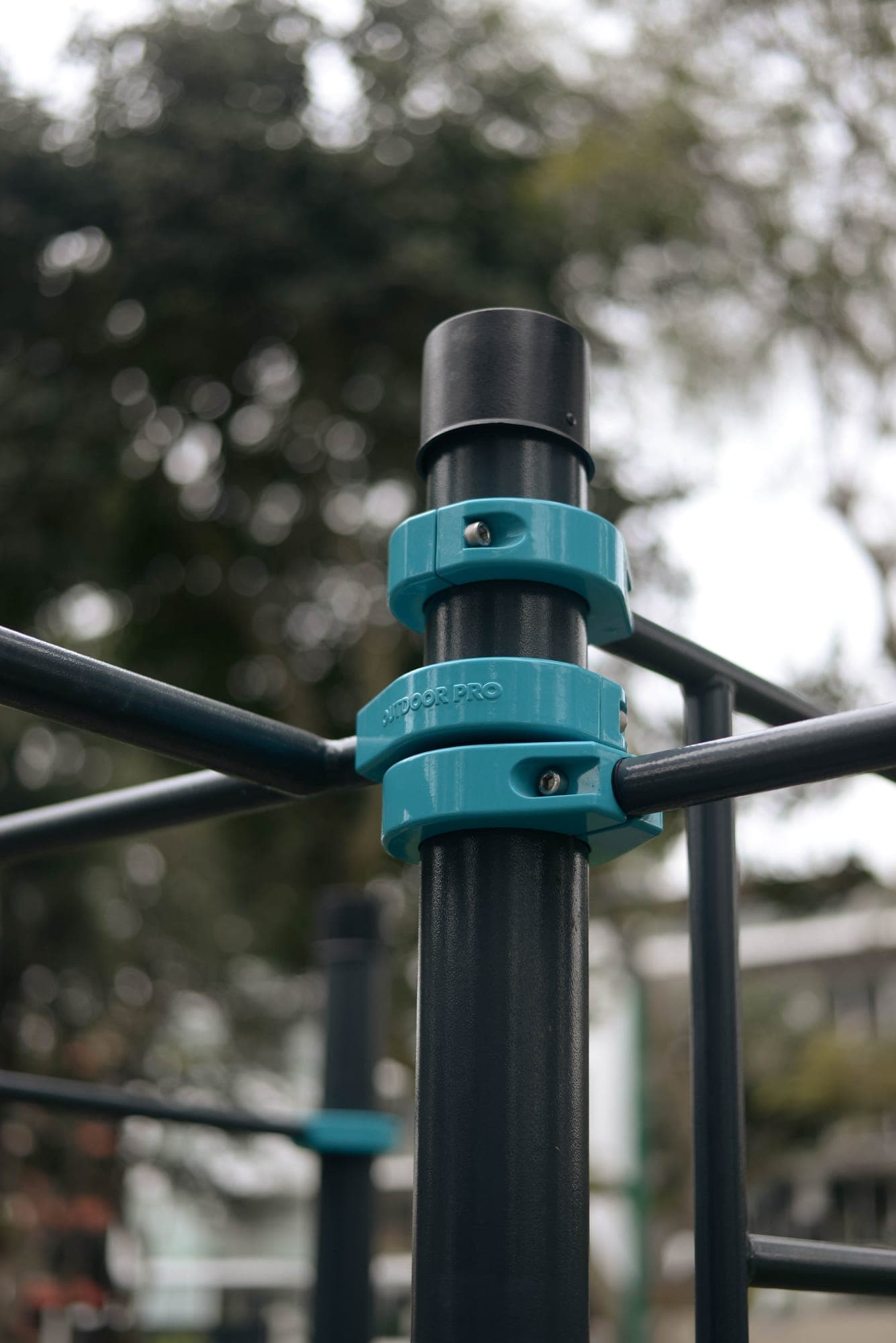 Detalle de dos abrazaderas OUTDOOR PRO turquesas en un poste